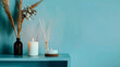 Reed diffuser with candle on shelf near color wall