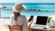 © AdriFerrer - A woman is sitting on a beach chair with a laptop