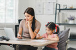 Young mother working from home while assisting her daughter with homework during daytime