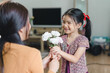 Happy mother's day concept. Young girl giving flowers to her mother in a cozy living room on mother's day.