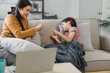 Mother and daughter enjoying playful hand game in a cozy living room setting.