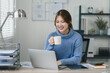 Smiling young woman enjoying a warm beverage during a break in a modern home office.