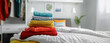 A stack of vibrant sweaters arranged on a bed in a stylish modern bedroom.