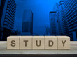 Study letter on wood block cubes on wooden table over modern office city tower and skyscraper, Business, education and learning concept