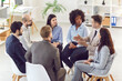 Group of diverse business people discussing work project sitting on chairs in a circle and talking on a meeting in office. Company employees talking about new startups. Team work concept.