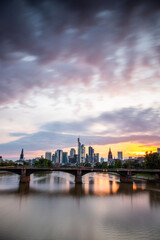 Wall Mural - View from a bridge over the River Main to a skyline in the financial district in the background as the sun sets. Twilight in Frankfurt am Main, Hesse Germany