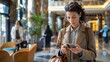 With her mobile device as her constant companion, the female business traveler efficiently handles her affairs, even in the bustling atmosphere of the hotel lobby.