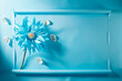 A conceptual floral art depicts a blue flower with petals falling against a blue monochromatic backdrop