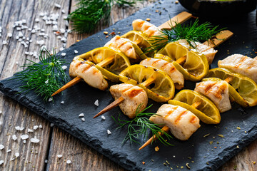 Poster - Poultry meat skewers - grilled meat with lime slices on wooden background
