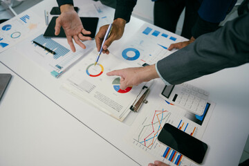 Fototapete - A group of people are looking at a table with graphs and charts
