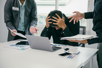 Poster - A man is sitting at a desk with a laptop and a stack of papers