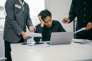 Poster - A man is sitting at a desk with a laptop and papers in front of him