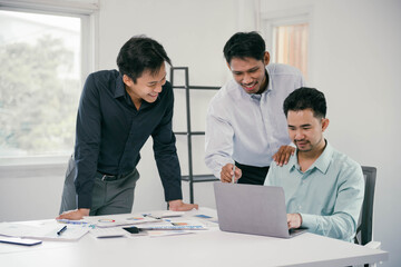Poster - Three men are sitting at a table with a laptop open in front of them