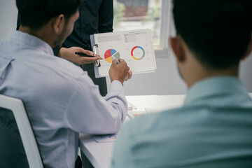 Fototapete - A man is showing a pie chart to two other men