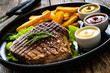 Grilled beef sirloin steak with French fries on wooden table
