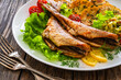 Fried sea bass with fried potatoes and fresh cabbage salad on wooden table

