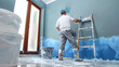 © Luluraschi - low angle rear view of professional painter painting a room, home renovation, makeover, feng shui