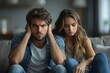 © Larisa AI - A young couple appears distressed and unhappy while seated on a grey sofa, expressing frustration