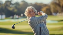 A Woman In A Gray Jacket Is Swinging A Golf Club On A Golf Course