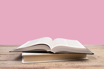 Wall Mural - open book. Composition with hardback books, fanned pages on wooden deck table and pink background. Books stacking. Back to school. Copy Space. Education background.