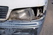 Damaged minibus headlight with worn plastic bumper