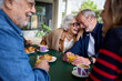 Romance in the elderly. Group of happy residents friends of a geriatric. Mature gray hair at coffee bakery cafe terrace at nursing home having fun breakfast. Caucasian senior citizens people together