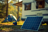 Fototapeta  - Portable solar panel positioned in the foreground at a tranquil campsite with an rv and tent in the softly focused background, harnessing renewable energy amidst nature