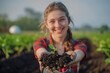 young woman holding a plant sprout with soil  in the field