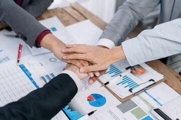 Leinwandbilder - A group of people are shaking hands on a table with a lot of papers and graphs