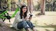 A woman is sitting on the grass with a green bicycle behind her