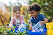 Children collecting plastic bottles for recycling in a garden. Natural light outdoor photography with copy space. Environmental awareness and education concept. Design for banner, poster, invitation