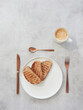 Top view of three slices of toast on white plate with coffee cup and bronze-colored silverware on gray background with copy space..