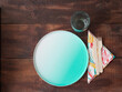 Single-use utensils for eating outdoors or at a picnic on wooden table. Disposable empty green cardboard plate, colorful paper napkin and biodegradable cutlery set, wooden fork and knife.