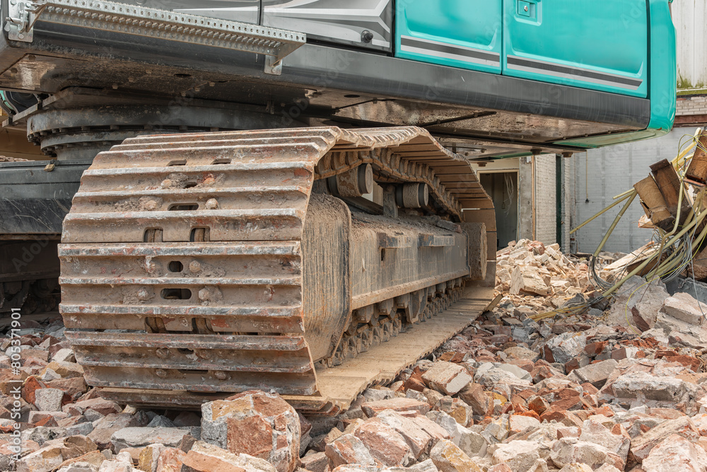 steel tracks of a mobile demolition crane standing on a mountain of stones