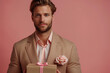 Man holding box with engagement ring on pink background