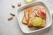 Serving tray with peanut butter and pear toasts, horizontal shot on a beige stone background with space, high angle view