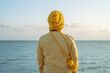 A woman with autumn style hat and yellow t-shirt by the sea on the coral reef.
