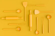Wooden kitchen utensils, tools and equipment on yellow monochrome background.