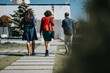 © qunica.com - Three professionals captured from behind while heading to an open-air business meeting under a clear sky.