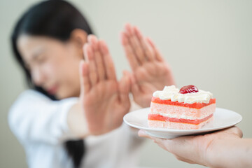 Sticker - Dieting young asian woman or girl use hand push out, dent sweet cake and control temptation for dessert.