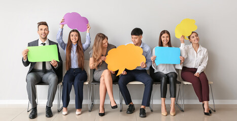 Wall Mural - Group of business people with blank speech bubbles near light wall