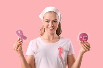 Wall Mural - Young woman with ribbon and bagged cookies on pink background. Breast cancer awareness concept