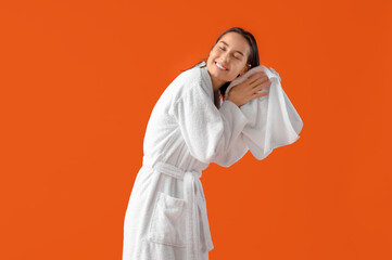 Sticker - Young woman in bathrobe wiping wet hair on orange background