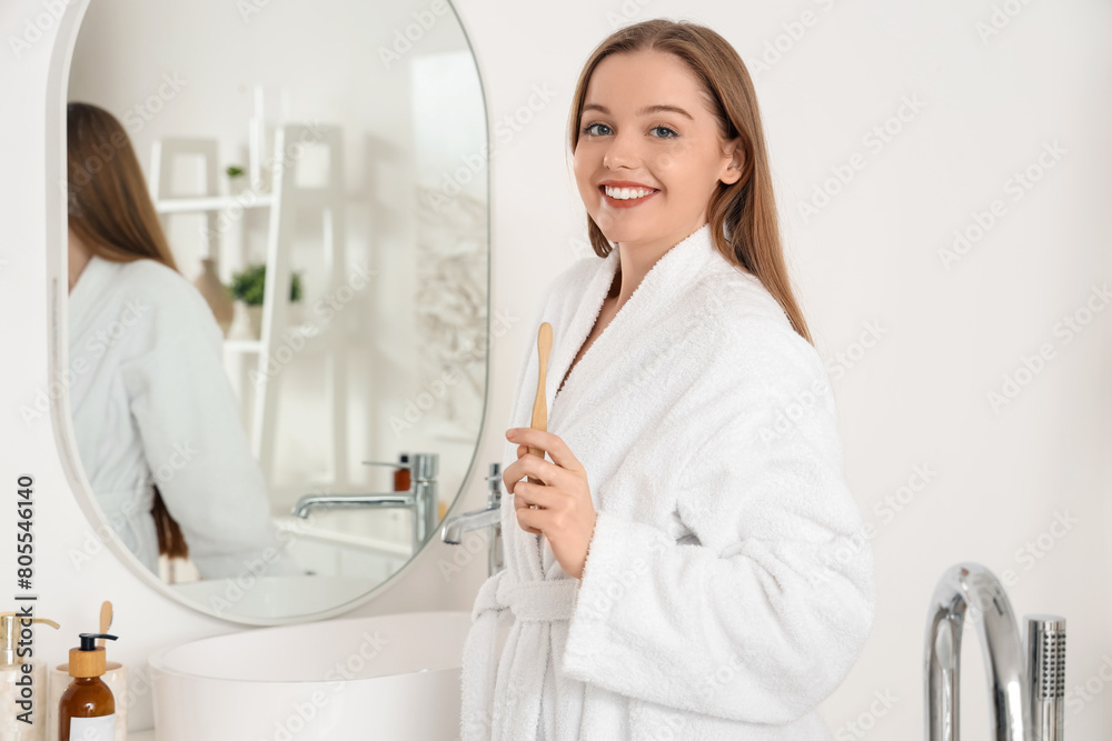 Young woman with toothbrush after shower in bathroom
