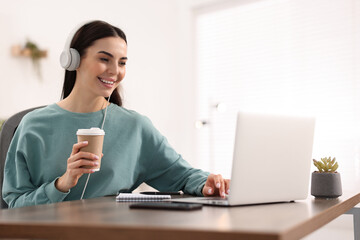 Poster - Young woman in headphones watching webinar at table in room