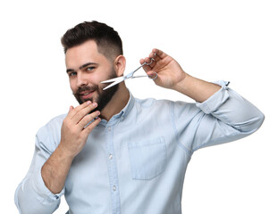 Wall Mural - Handsome young man trimming beard with scissors on white background