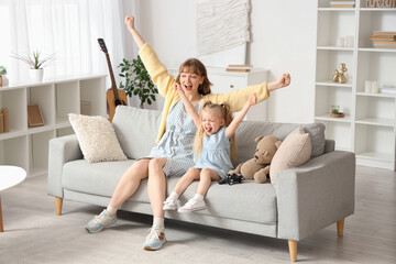 Sticker - Nanny with little girl playing video game on sofa at home