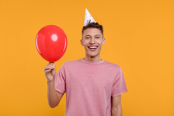 Poster - Happy man in party hat with balloon on orange background