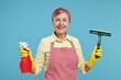 © New Africa - Happy housewife with spray bottle and squeegee on light blue background