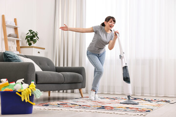 Poster - Happy young housewife having fun while cleaning at home